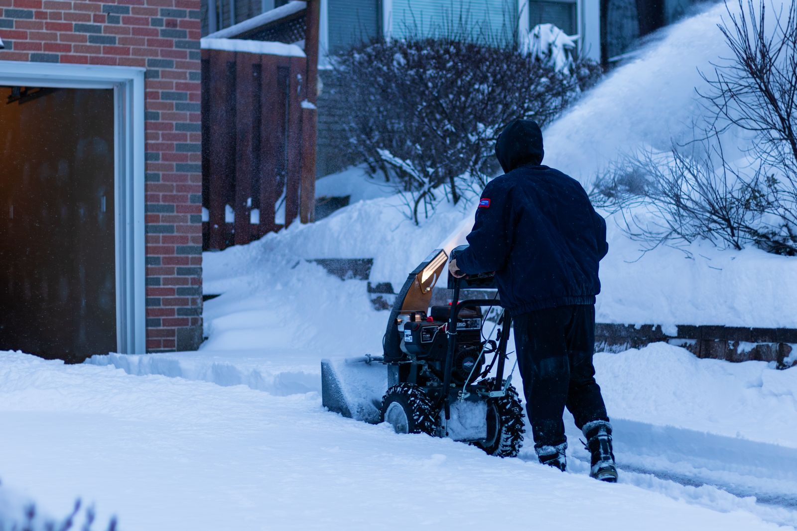 Crew member clearing a sidewalk with a snow blower