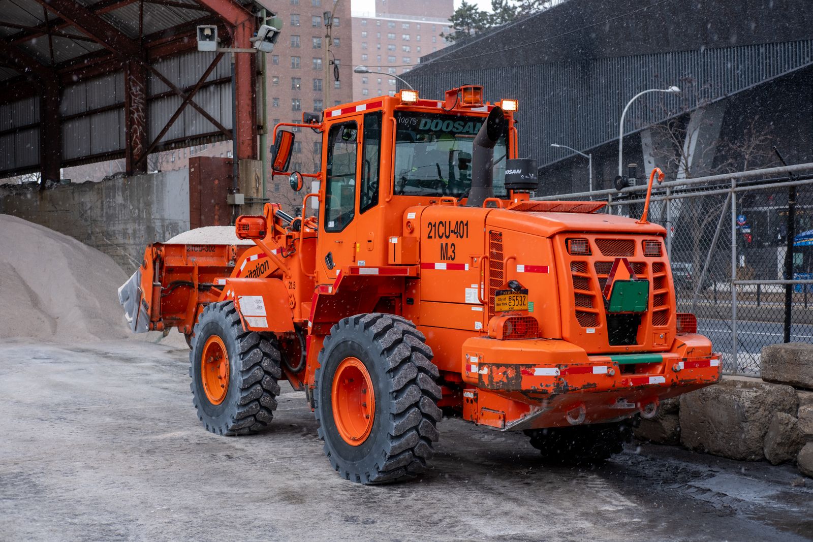 Wheel loader clearing a commercial parking lot in the city