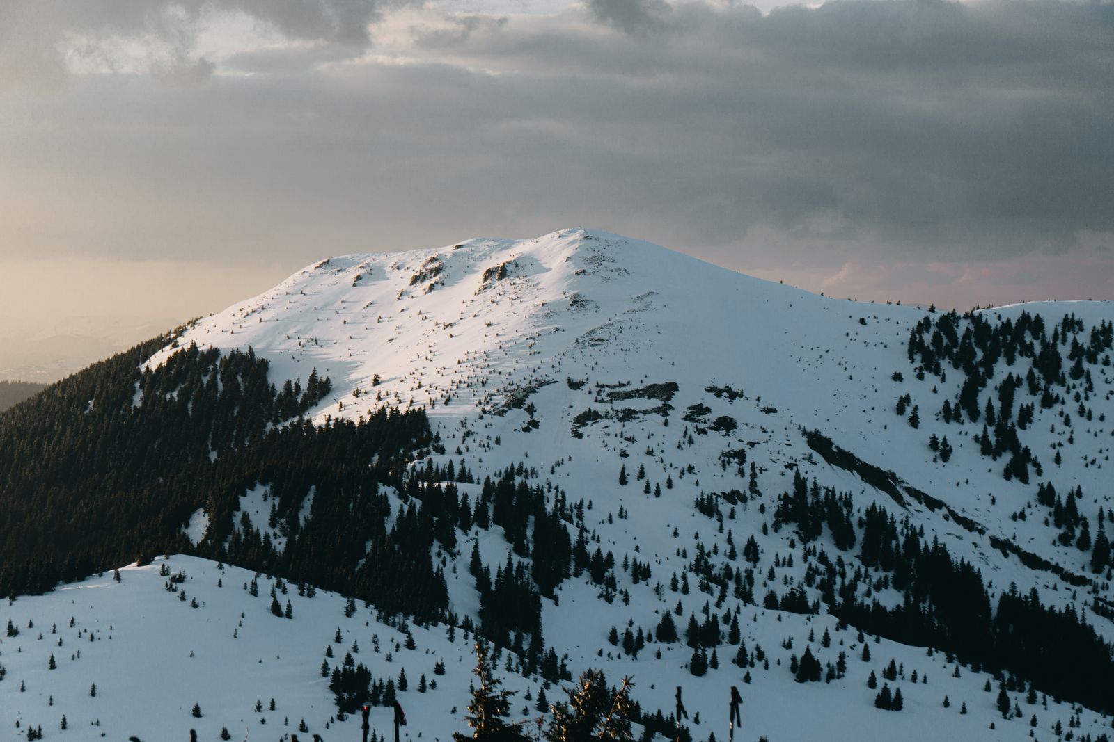 Snow-covered mountain peak under a moody winter sky at dusk