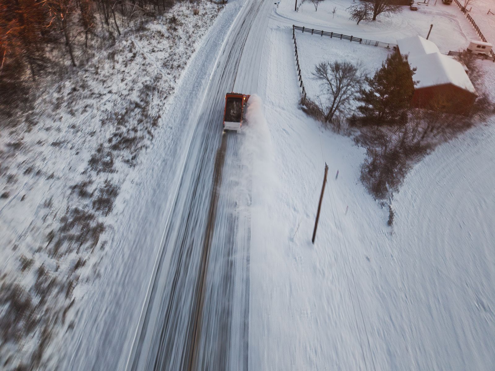 Aerial view of a snowplow clearing a snow-covered road