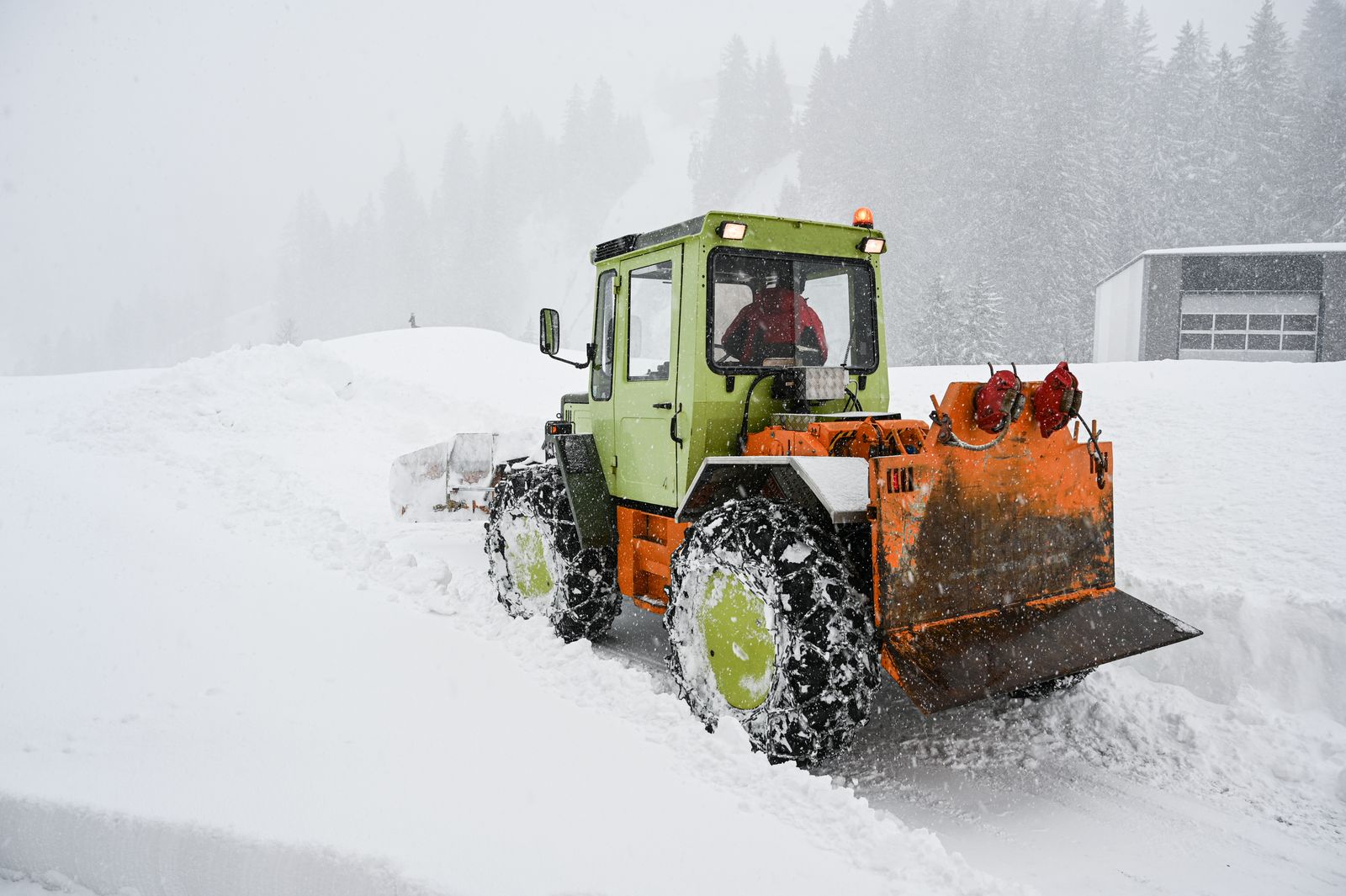 Plow working through heavy snowfall in a storm on a frosty day