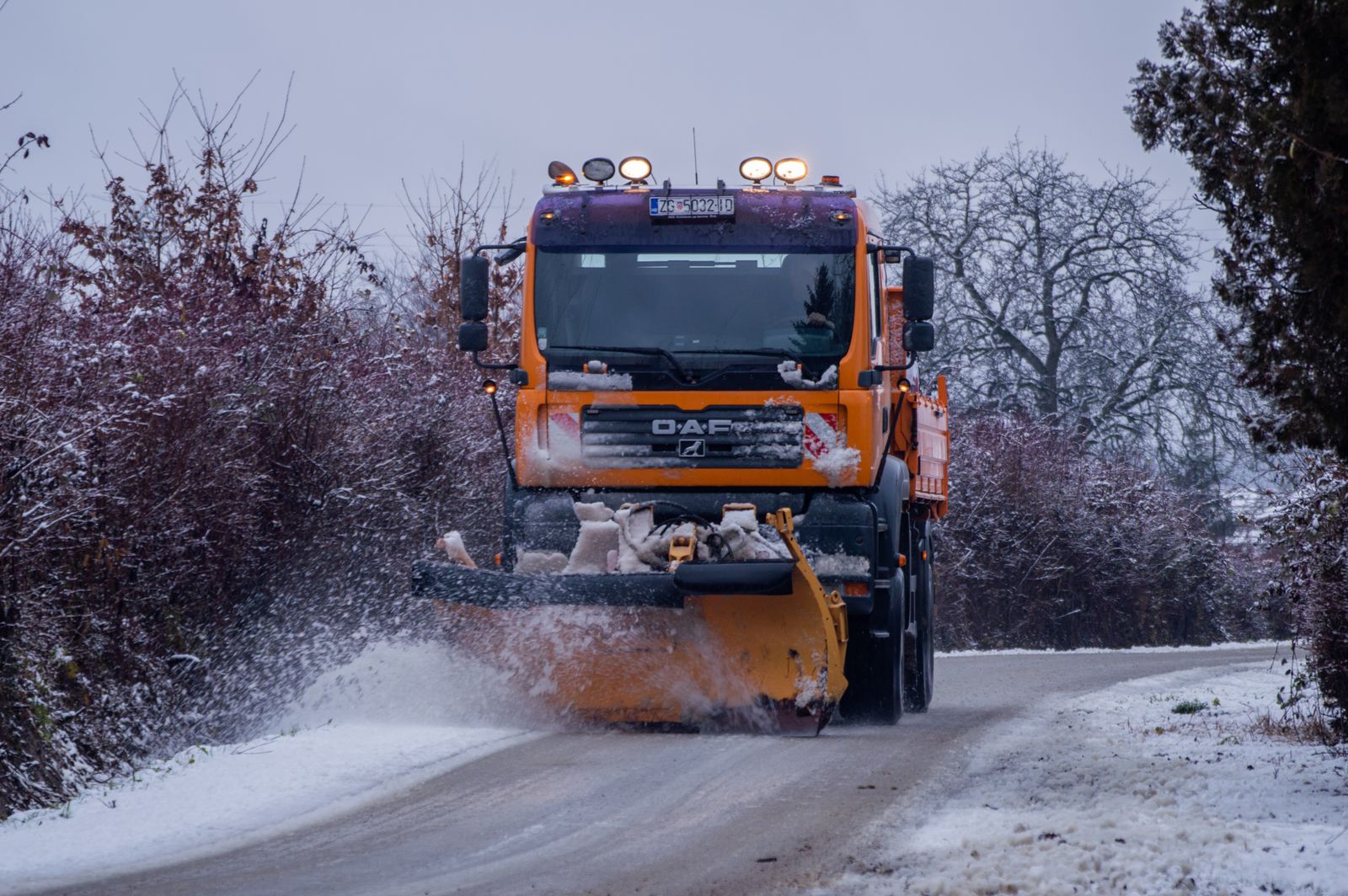 Plow truck clearing a snow-covered rural road