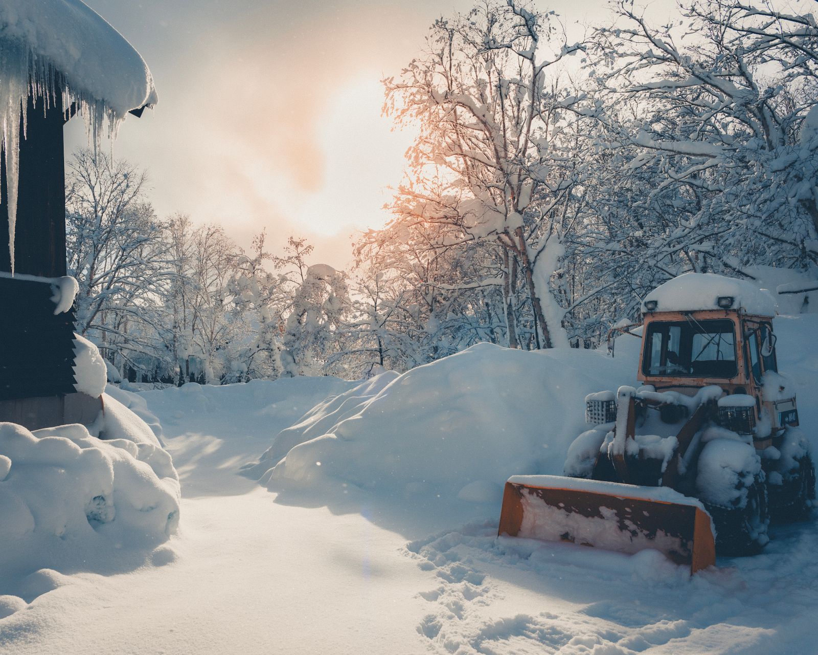 Spreader working across a snow-covered property at sunrise