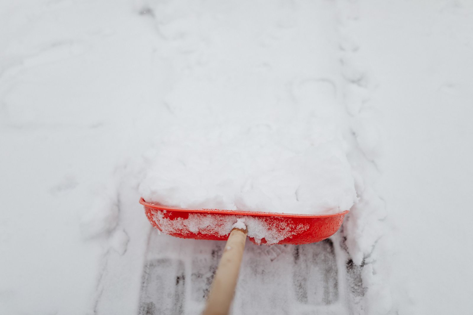 Close-up of a shovel cutting through fresh snow on a residential driveway